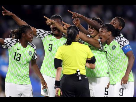 Nigerian players points towards the electronic screen as they protest a yellow card and a penalty awarded against their goalkeeper, Chiamaka Nnadozie, by referee Melissa Borjas of Honduras (centre) during their FIFA Women’s World Cup Group A clash with hosts France at the Roazhon Park in Rennes yesterday.