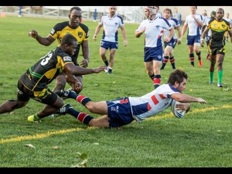 The Reggae Warriors’ Leon Thomas (left) and Jermaine Pinnock (second left) attempt to prevent the USA Hawks from scoring a try during a recent rugby league game in Florida. 
