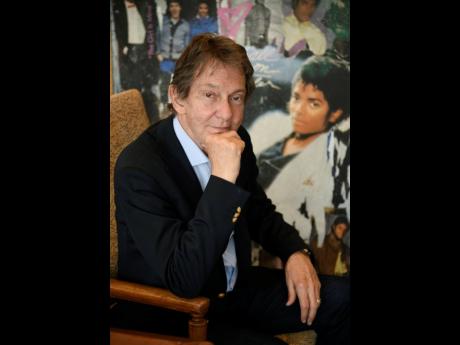 In this Tuesday, June 18, 2019 photo, entertainment and corporate lawyer John Branca, the co-executor of Michael Jackson’s estate, poses in his office, at the law firm of Ziffren Brittenham LLP in Los Angeles, next to an artwork presented to him from Sony Music commemorating the sale of 100 million copies of Michael Jackson’s album ‘Thriller’.  . 
