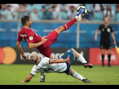 Qatar’s Boualem Khoukhi (above) and Argentina’s Sergio Aguero fight  for the ball during a Copa America Group B match at the Arena do Gremio in Porto Alegre, Brazil, yesterday.  