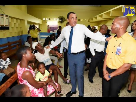 Health Minister, Dr. Christopher Tufton (second right), interacts with Dr. Richard Manning (right) and patients of the Seaview Gardens Health Centre in Kingston  during a ceremony on April 30, when the clinic was formally adopted by Massy Distribution (Jamaica) Limited under the Ministry of Health’s Adopt-a-Clinic programme. 