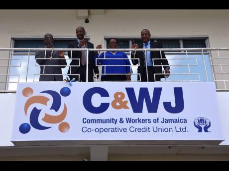 Representatives of Community & Workers of Jamaica Co-operative Credit Union unveil a new sign in St Elizabeth in 2018 following its merger with the parish’s credit union. CEO Carlton Barclay is at right.