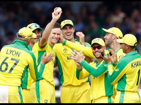 Australia’s Jason Behrendorff holds up the ball as he celebrates with teammates after taking the wicket of England’s Jofra Archer during the Cricket World Cup match at Lord’s cricket ground in London, yesterday. Australia won by 65 runs, with Behrendorff taking five wickets. 