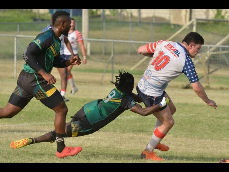 Steve Miller of the Jamaica Reggae Warriors tackles Kyle Denham (right) of the USA Hawks during a Rugby League friendly match held at the UWI Bowl on Saturday. Jamaica won 26-24.