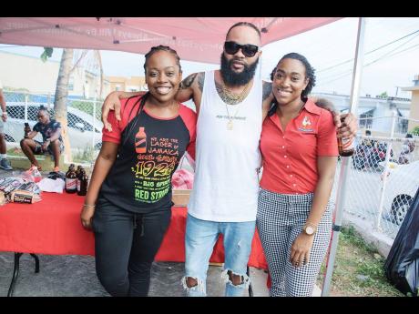 Reshima Kelly, junior brand manager for Red Stripe, shares a moment with Chicken and Beer (centre) and Nicole Hall, marketing coordinator at CB Foods, at the community launch of their summer promotion, ‘Chicken and Beer’, in Nannyville. 