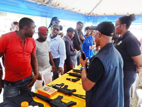 Persons gather at the Customs Agency booth that has on display some items that are banned.