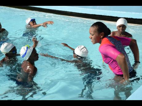 Alia Atkinson teaching children to swim at a clinic held at the University of The West Indies swimming pool on Tuesday, December 19, 2017.  