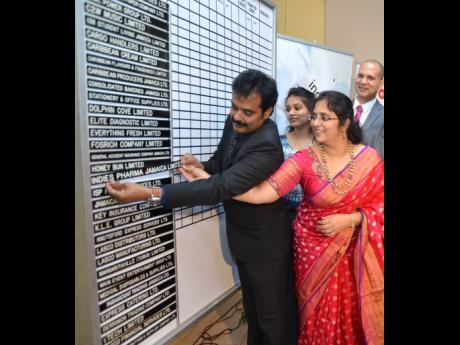 In this August 2018 Gleaner file photo, husband and wife business partners Guna Muppuri and Vishu Muppri insert the Indies Pharma strip on the listing board at the Jamaica Stock Exchange. .