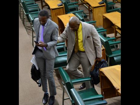 Senator Dr André Haughton (left) assists his colleague Dr Floyd Morris, who is visually impaired, to leave the House floor as opposition members walked out of the Senate yesterday.