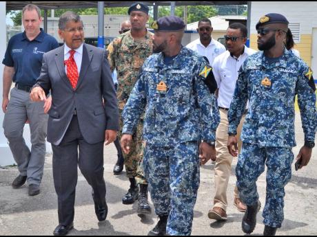 British High Commissioner Asif Ahmad (left) engages LCdr Aceion Prescott (centre), commanding officer of the Jamaica Defence Force Coast Guard, and other officers as he arrives at the Coast Guard base in Port Royal, Kingston.