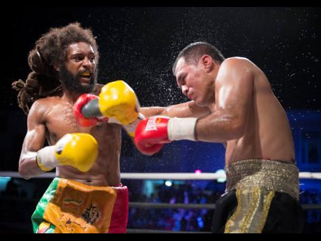 Jesus Laguna of Mexico (right) is dealt damage by a left hook from Headley ‘Light’ Scott in the feature event at the Gloves Over Guns fight night held at the Ambassador Theatre in Trench Town, Kingston, on Saturday. 