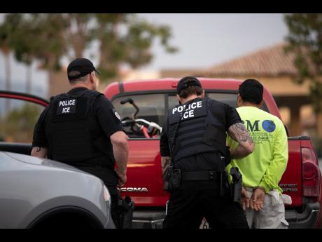 In this July 8, 2019 photo, US Immigration and Customs Enforcement officers detain a man during an operation in California. The carefully orchestrated arrest last week in this San Diego suburb illustrates how President Donald Trump’s pledge to start deporting millions of people in the country illegally is virtually impossible with ICE’s budget and its method of picking people up, according to critics.