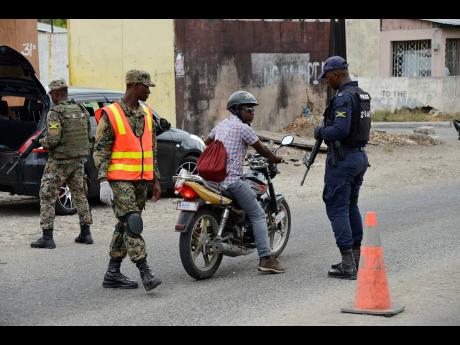 Members of the Jamaica Defence Force and the Jamaica Constabulary Force manning a security checkpoint along a section of Waltham Park Road under the state of emergency in the St Andrew South Police Division on July 10.