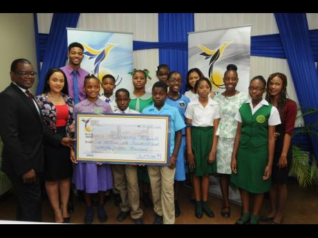 Wayne Mckenzie (left), president and CEO of West Kingston Power Partners & Jamaica Energy Partners (JEP), and Melissa Newman (second left), public and community relations specialist, handing over the cheque to recipients  from west Kingston. The scholarships, which were awarded to more than 30 secondary and tertiary-level students, were presented at the JEP head office on Marcus Garvey Drive in Kingston.