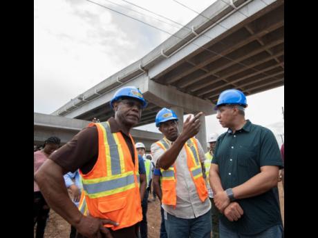 Prime Minister Andrew Holness in dialogue with E.G. Hunter (left), chief executive officer of the National Works Agency, and Varden Downer (centre), acting deputy director of project implementation, at the overhead bridge in Three Miles, one of five locations visited by the prime minister yesterday. 