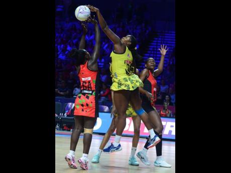 Jamaica’s Stacian Facey (centre) makes a big block on Malawi goal attack Jane Chimaliro (left) while Malawi goal shooter Sindi Simtowe (right) prepares herself for a possible rebound during their fifth-place match in the Vitality Netball World Cup at the M&S Bank Arena in Liverpool, England, yesterday. 