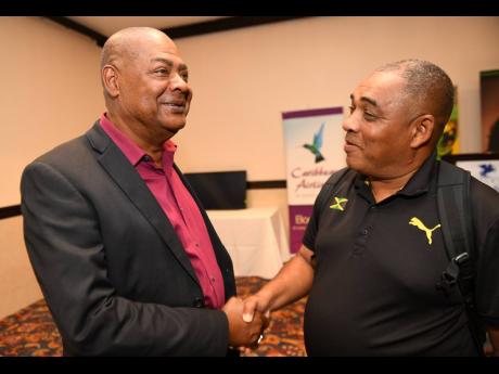 From left: Jamaica Football Federation President Michael Ricketts greets Reggae Girlz head coach Hue Menzies ahead of a press conference held at the Jamaica Pegasus yesterday, where the members of the country’s women’s football team for the Pan Am Games were introduced.
