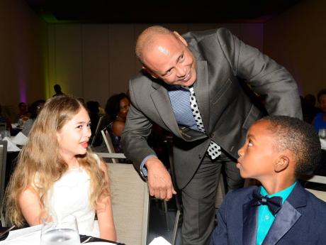 Guardian Life Limited President Eric Hosin speaks with Rachel Gammon, the top-performing girl in the inaugural PEP exams, and Dominic Haisley, the top boy, at the annual Guardian Group Scholarship Awards luncheon at the AC Marriott Hotel in St Andrew yesterday.