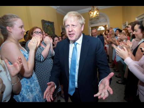 Britain’s new Prime Minister Boris Johnson is welcomed into 10 Downing Street by staff in London, on Wednesday, July 24. 