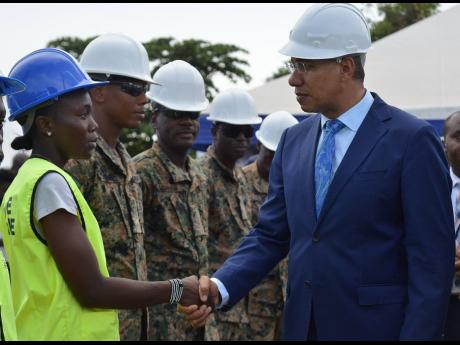 Prime Minister Andrew Michael Holness greets Mashekia McKenzie, a trainee with the Housing, Opportunity, Production and Employment (HOPE) programme, during a tour of the new police station on Olympic Way, a site where unattached youth are trained under the HOPE  programme. 