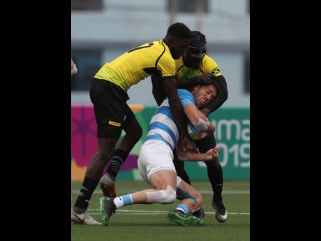 Franco Sabato (centre), of Argentina, is tackled by Mikel Facey (left), and Oshane Edie, of Jamaica, during their Rugby Sevens match at the Pan American Games in Lima, Peru, yesterday. Argentina won the match 52-0. 