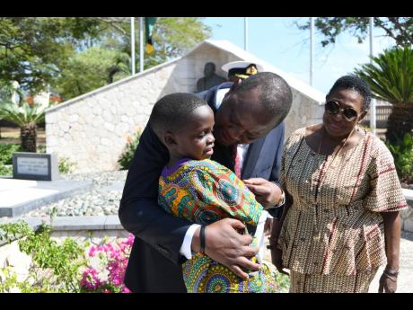 Uhuru Kenyatta, president of the Republic of Kenya, chats with Chavon Brown as Culture Minister Olivia Grange looks on at the floral tribute at shrine of National Hero Marcus Garvey at National Heroes Park in Kingston yesterday.