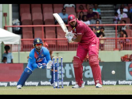 West Indies batsman Kieron Pollard (right) makes a shot as India wicket-keeper Rishabh Pant looks on during their third T20 international cricket match in Providence, Guyana, yesterday. Pollard struck 58 runs as the Windies lost by seven wickets.