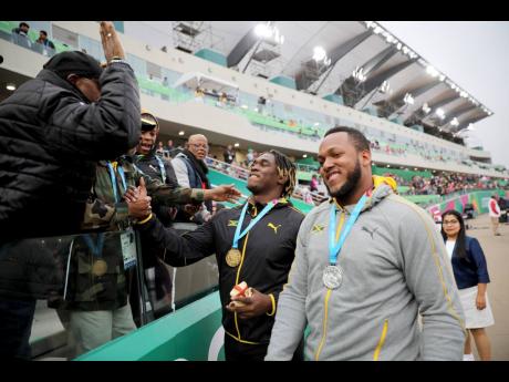 Jamaica’s Fedrick Dacres is greeted by coaches and fans after receiving his gold medal for the men’s discus throw competition during the Pan American Games in Lima, Peru, Tuesday, August 6, 2019. At right is friend and silver medallist Traves Smikle, also of Jamaica.  