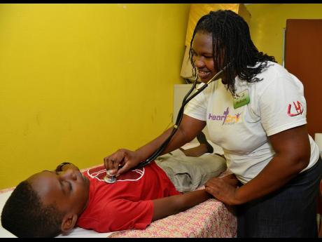 Dr Kerean Nelson (right), Medical Microbiology Resident, checks the temperature of Hekyle Moore, 10-year-old student from St Richards Primary School, during the Franklin Town New Testament Church of God/Care and Feed My Sheep Inc. Health Fair, held at the church last Thursday, Emancipation Day. 