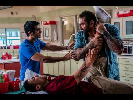 This image released by 20th Century Fox shows Dave Bautista (right) and Kumail Nanjiani (standing at left) in a scene from ‘Stuber’. 