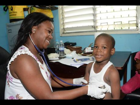 Dr Trudy-Ann Johnson, a member of the Rotaract Club of New Kingston, examines Olando Brown during the eighth staging of the Maverley Health Fair by the Rotary Club of Trafalgar New Heights in the community recently. 