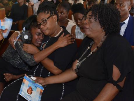 
From left: Sharon Campbell (sister) is comforted by Marlene Young (wife) and Grace Smith (sister-in-law) at the thanksgiving service for Anthony ‘TY’ Young at the Good Tidings Mennonite Church in St Andrew yesterday. 