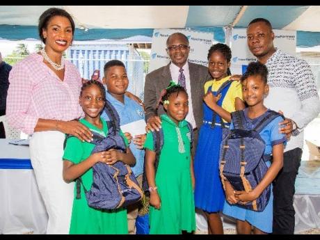 These students are all packed and ready for school after receiving backpacks pre-packed with notebooks, pens and pencils during New Fortress Energy’s back-to-school fair in Old Harbour Bay recently. Standing with the joyful students are  (from left) Verona Carter, vice-president, public affairs, New Fortress Energy; Everald Warmington, member of parliament for South Western St Catherine; and George Goode, principal, Old Harbour Primary School.