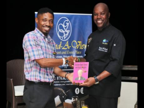 Bertland Hope (left), son of Professor Donna Hope, presents a copy of his mother’s book, ‘Chicken Back Gravy and Such Delights’, to executive chef and host Dennis McIntosh during the book’s launch at the Grand-A-View Restaurant in Montego Bay recently. 