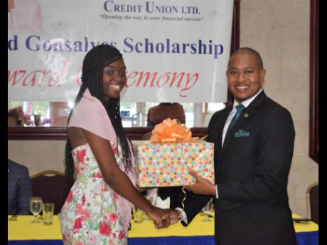 Minister of State in the Ministry of Industry, Commerce, Agriculture and Fisheries  Floyd Green receives a gift basket from former scholarship recipient Shannaia McDowell following his keynote address at the Gateway Co-operative Credit Union-sponsored Enid Gonzales Primary Exit Profile Scholarship Luncheon and Awards ceremony in St James last week Thursday. 