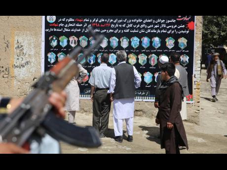 Afghans look at a banner displaying photographs of victims of the Dubai City wedding hall bombing during a memorial service, in Kabul, Afghanistan, Tuesday, Aug. 20, 2019. Hundreds of people have gathered in mosques in Afghanistan’s capital for memorials for scores of people killed in a horrific suicide bombing at a Kabul wedding over the weekend.(AP Photo/Rafiq Maqbool)