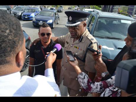 Assistant Commissioner of Police Bishop Dr Gary Welsh, head of the Public Safety and Traffic Enforcement Branch, speaking with reporters as driver Dennis Dietrih looks on yesterday.