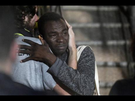 A man cries as he hugs a crew member after disembarking from the ‘Open Arms’ rescue ship on the Sicilian island of Lampedusa, southern Italy, on Tuesday. 