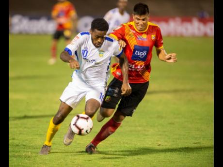 Waterhouse FC's Kendroy Howell (left) dribbles to goal, but is challenged by CS Herediano midfielder Esteban Granados during their Scotiabank Concacaf League match at the National Stadium earlier this evening.