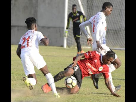 Romario Campbell (centre), representing Mount Pleasant Academy, goes down under the challenge of the Portmore United pair of Donnegy Fer (left) and Chavany Willis (right) during their Red Stripe Premier League football match at the Spanish Town Prison Oval on Sunday, January 6, 2019.