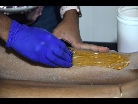 Richelle Parchment applying the sugar paste to her client’s leg. 