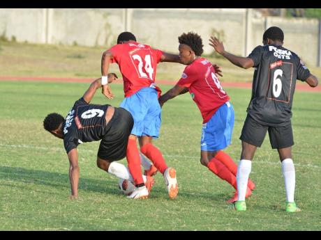 Cavalier striker Alex Marshal (left) tries to get away from  Deandre Thomas (right) and Kemar Philpotts, both of  Dunbeholden, during Sunday’s Red Stripe Premier League encounter at Stadium East. Cavalier won the game 3-1.