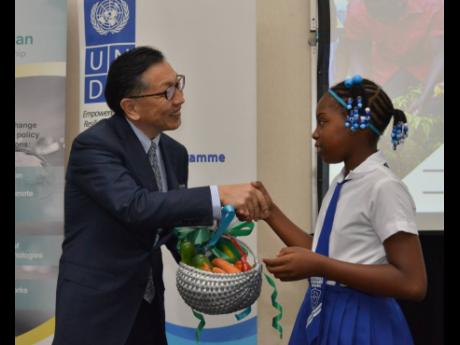 Hiromasa Yamazaki, ambassador of Japan to Jamaica, is overcome with emotions as he is presented with a basket by Anya Downes, from Richmond Park Primary School, during the closing ceremony of the Japan-Caribbean Climate Change Partnership at the Spanish Court Hotel in St Andrew yesterday.