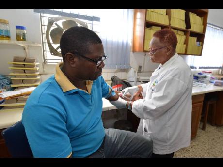 Nurse Sandra McDonald draws blood from Roger Barrett to conduct a test during the prostate cancer awareness health fair held at the Jamaica Cancer Society’s Lady Musgrave Road offices in St Andrew yesterday.