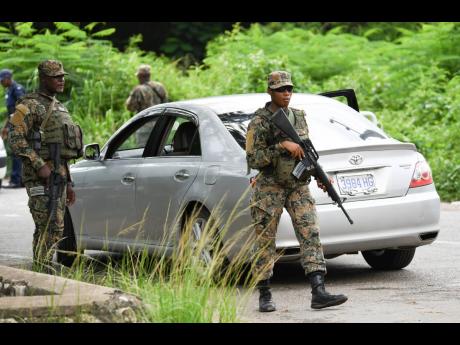Jamaica Defence Force soldiers on duty in Sevens Heights, Clarendon, yesterday after a state of public emergency was declared in the parish.