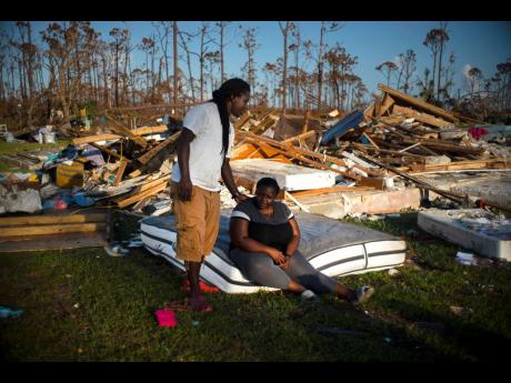 Synobia Reckley pauses on a wet mattress on Sunday as her husband, Dexter Edwards, consoles her amid the remains of their home, which was destroyed by Hurricane Dorian in Rocky Creek East End, Grand Bahama, The Bahamas.