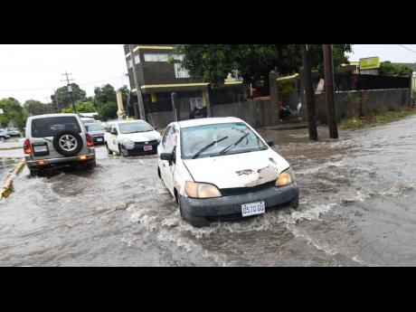Motorists slowly traverse a flooded Maxfield Avenue in St Andrew on Monday as heavy rainfall inundated several Corporate Area roads.