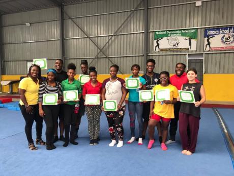 Jamaica Amateur Gymnastics Association president Nicole Grant-Brown (left) stands with 11 coaches certified in the National Gymnastics Federation of Jamaica Level One course, which took place recently at the National Gymnasium in Kingston.