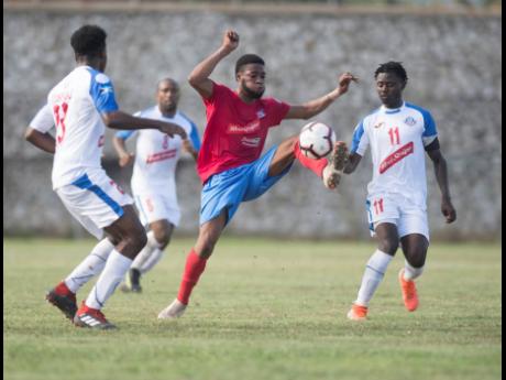 Dunbeholden FC’s Dean-Andre Thomas (centre) controls the ball ahead of advancing Portmore United players Emilio Rousseau (left), Damion Williams (second left), and Andre Lewis during their Red Stripe Premier League match at the Spanish Town Prison Oval in Spanish Town, St Catherine, yesterday. 