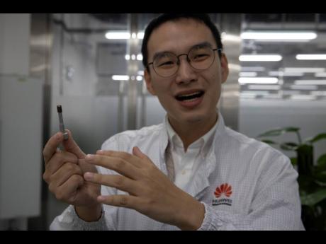 In this August 21, 2019 photo, a Huawei research engineer holds up a coated screw designed to reduce signal interference at the Huawei materials lab in Dongguan in Southern China’s Guangdong province. 